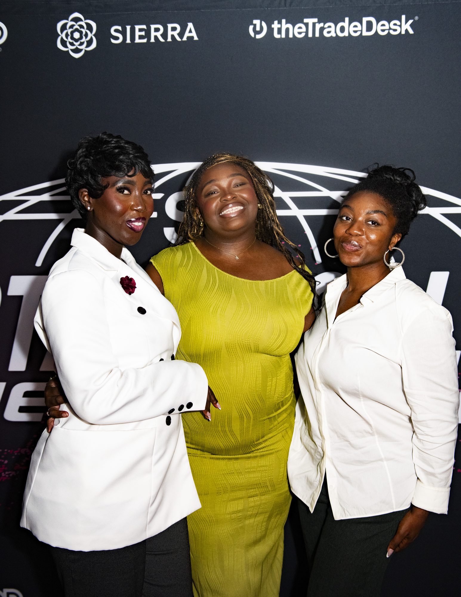 Three guests posing together at the step-and-repeat