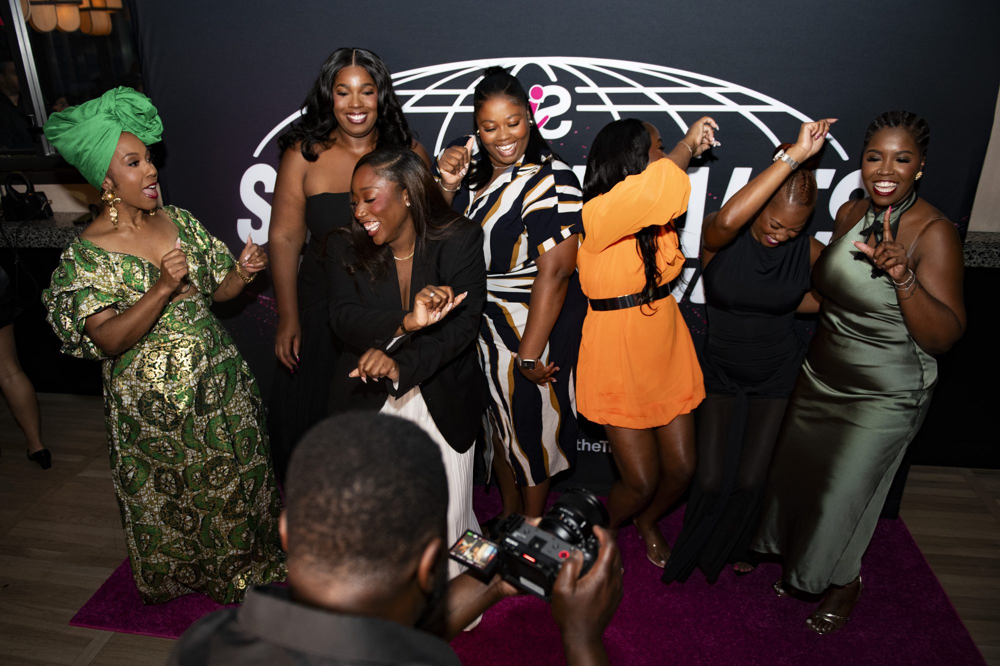 Group of guests dancing at the step-and-repeat as a photographer shoots