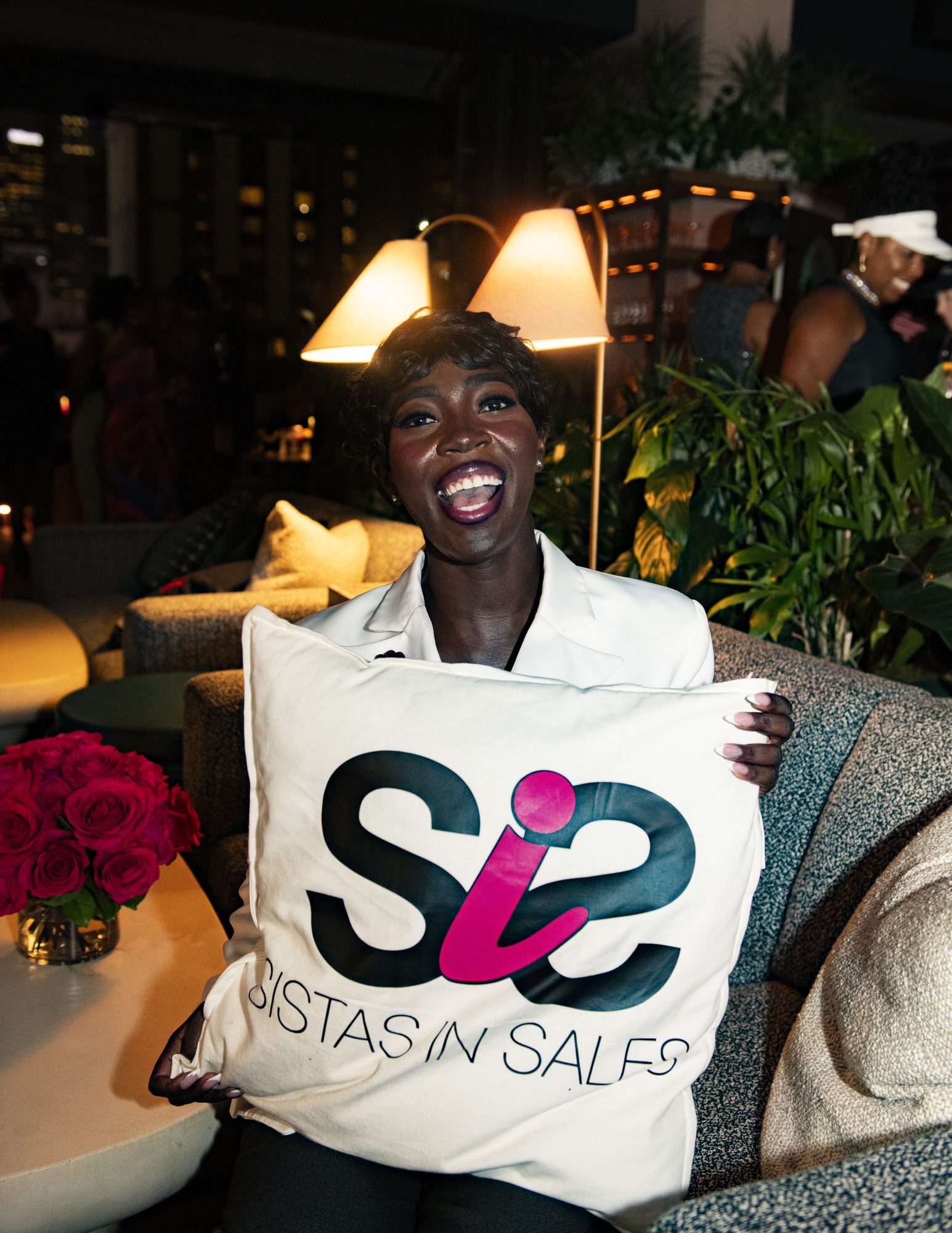 Guest smiling while holding a Sistas in Sales pillow