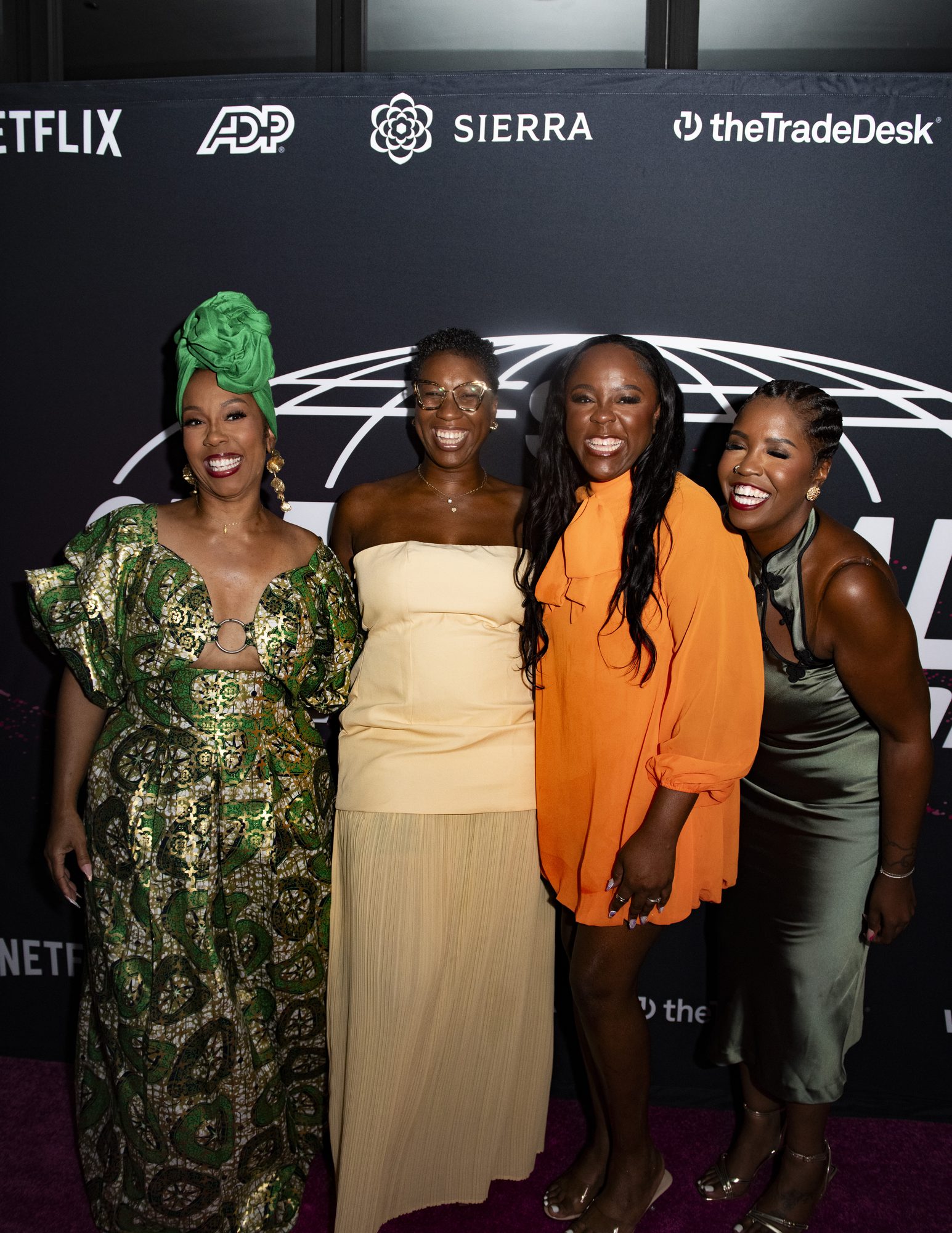 Four guests posing together at the step-and-repeat with partner logos