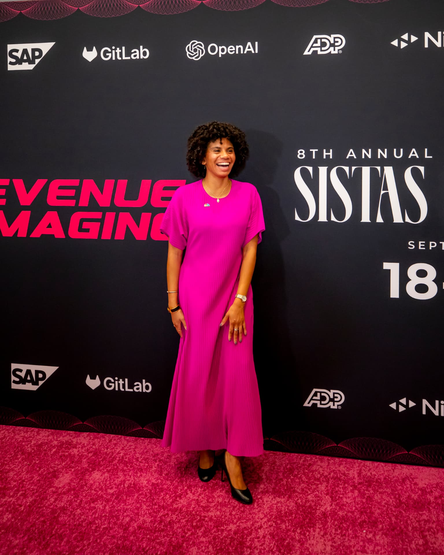 Attendee on the pink carpet in a hot pink pleated midi dress with black heels