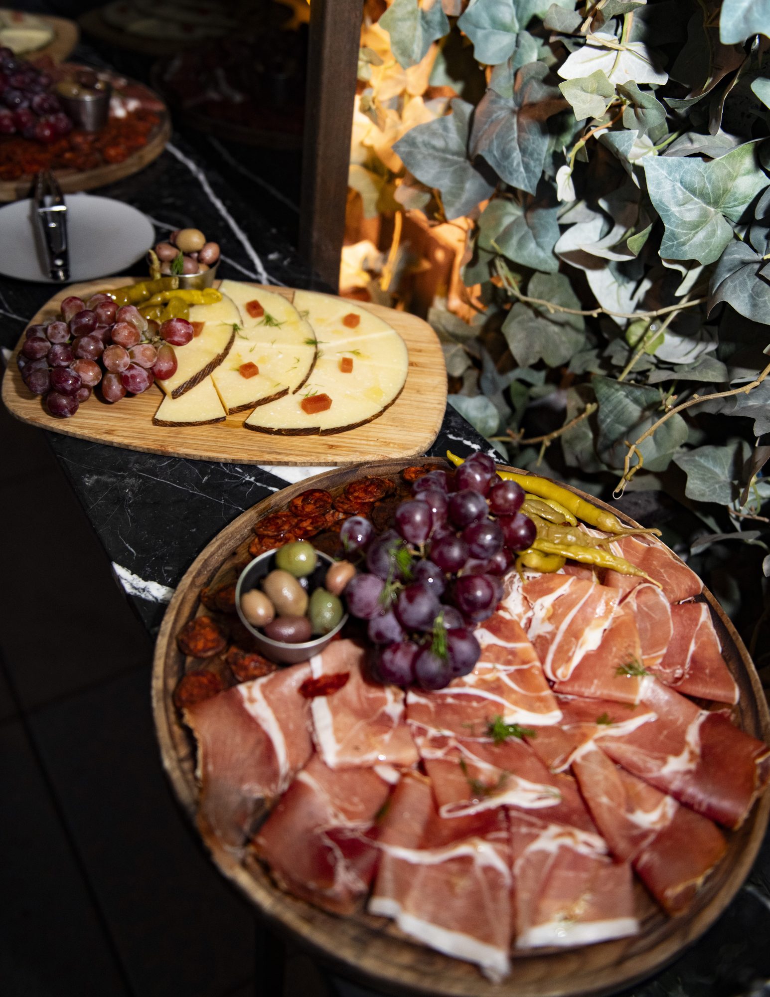 Charcuterie boards with cured meats, cheeses and grapes framed by ivy