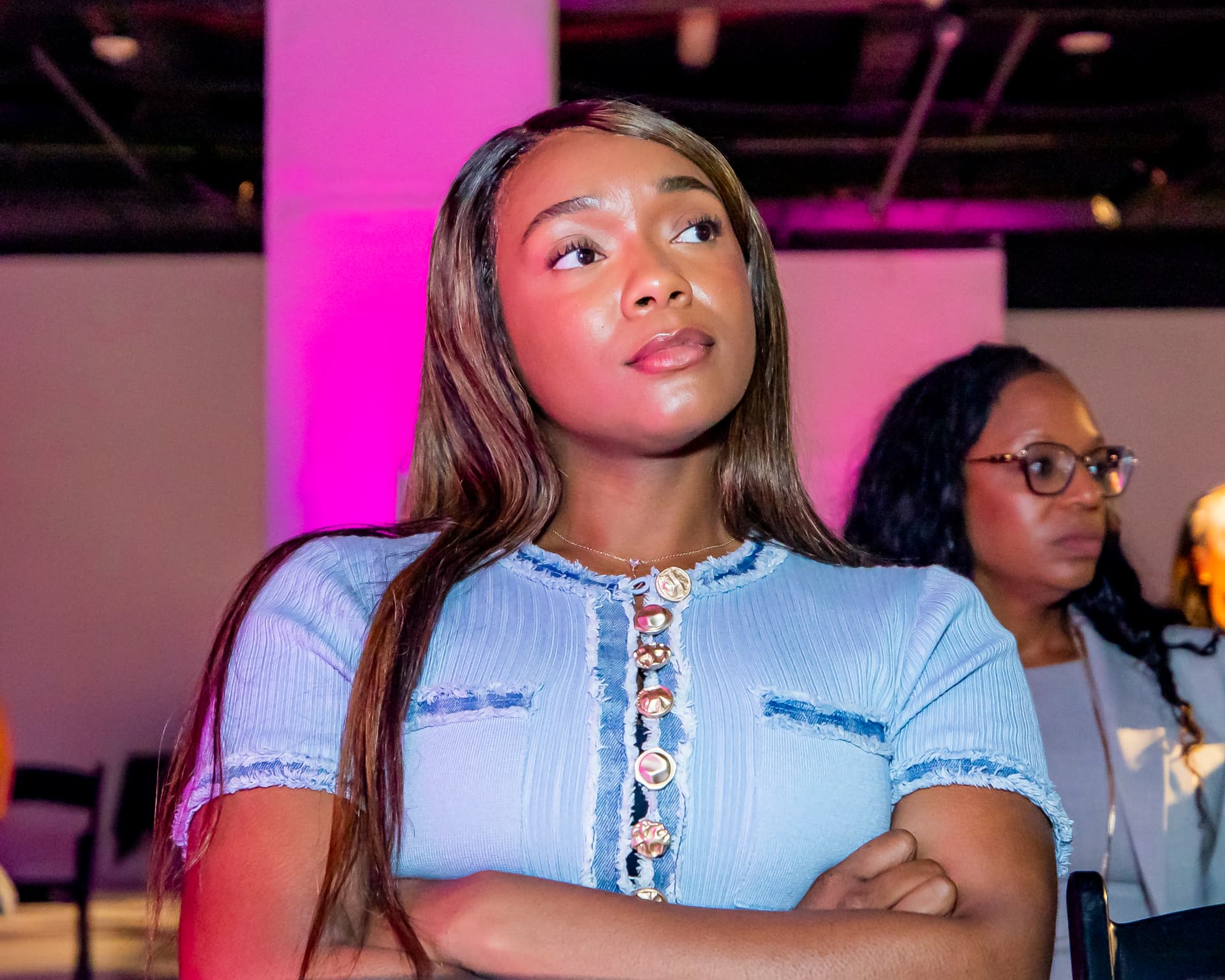 SIS attendee in a light blue short-sleeve dress with button detail, arms crossed