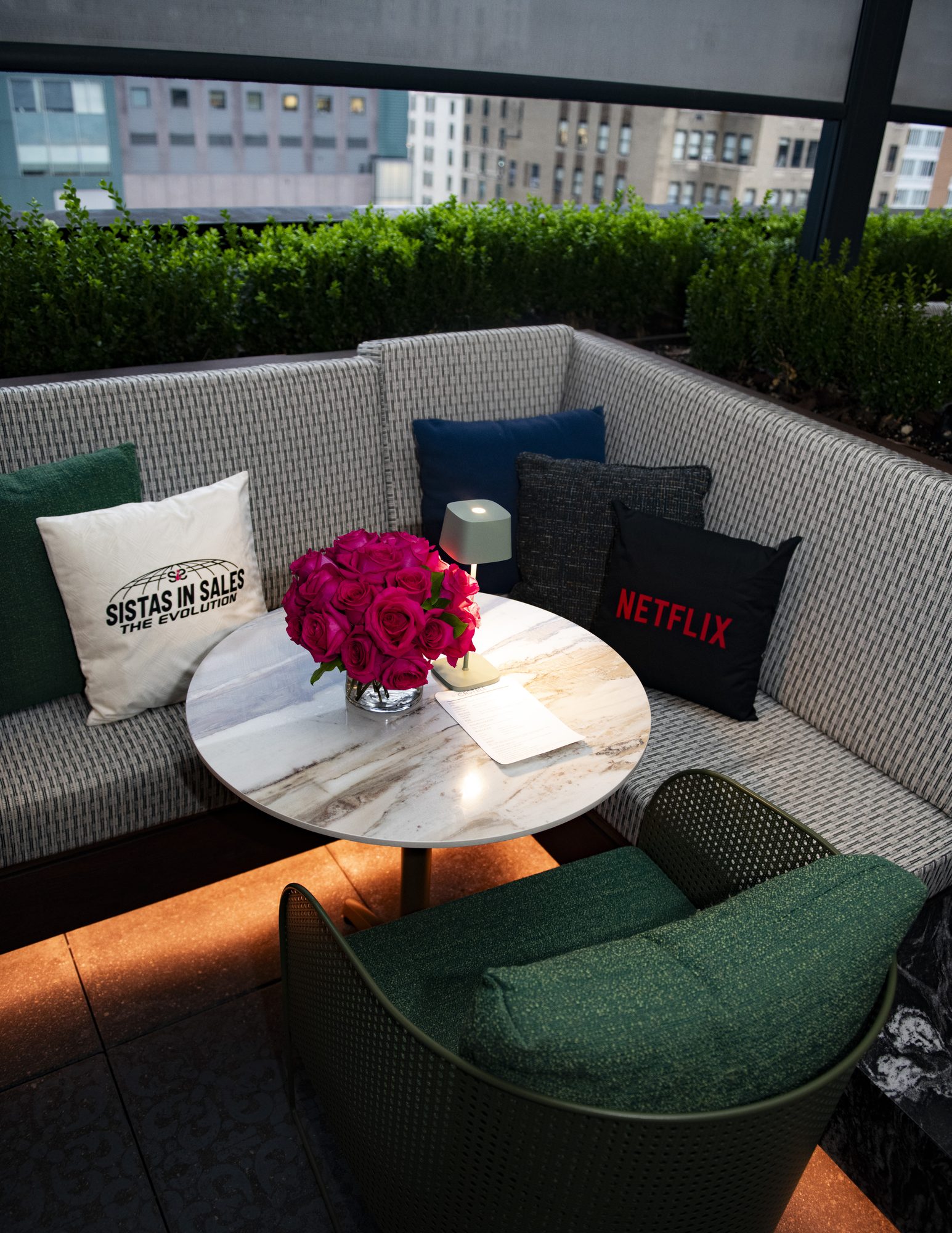 Rooftop lounge set with Netflix and Sistas in Sales pillows and pink roses