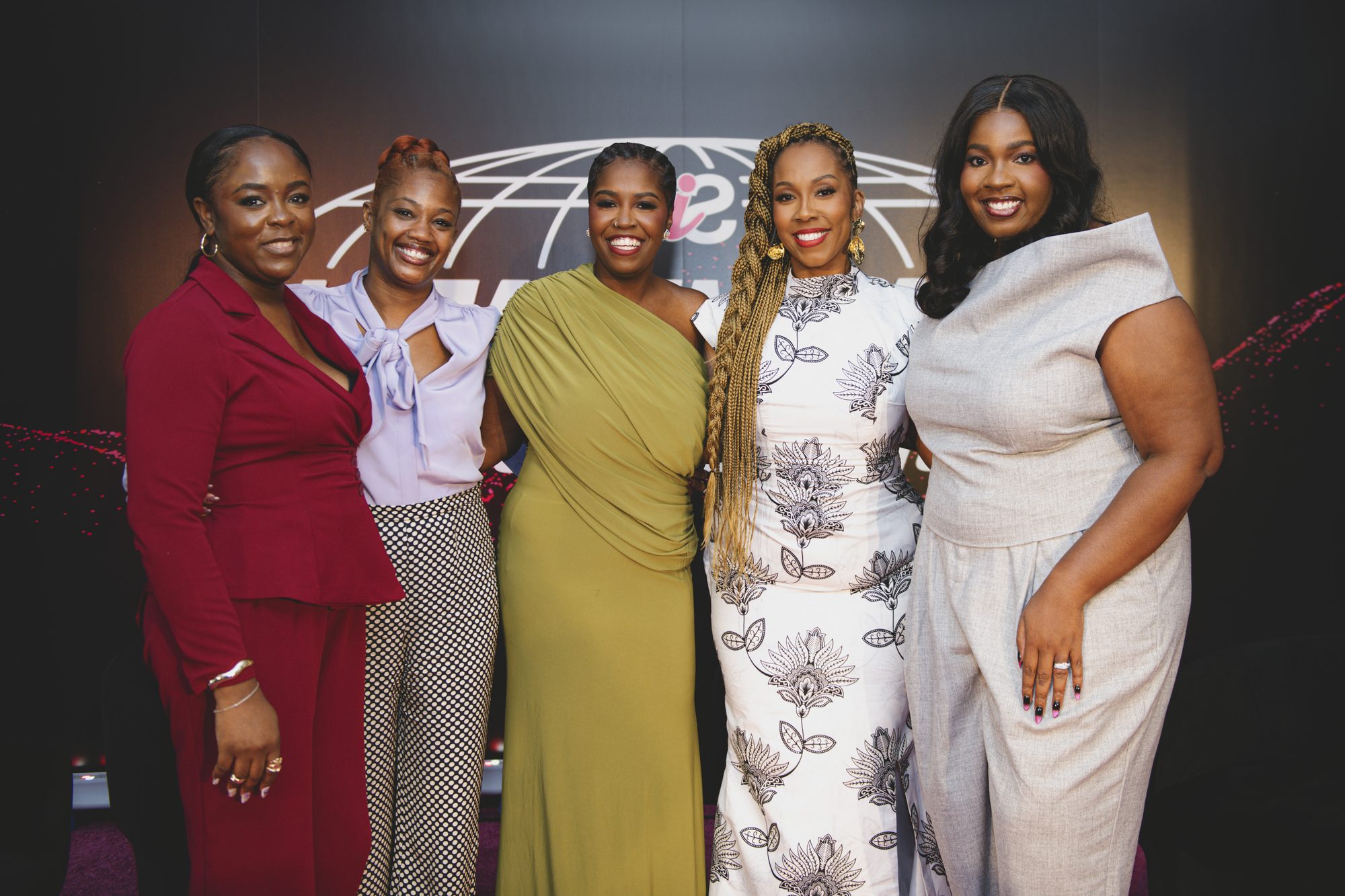 Group of five women posing together on the pink carpet