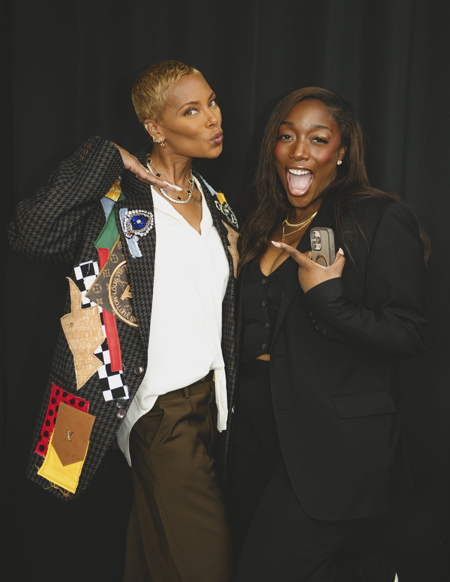 Two women striking playful poses together backstage