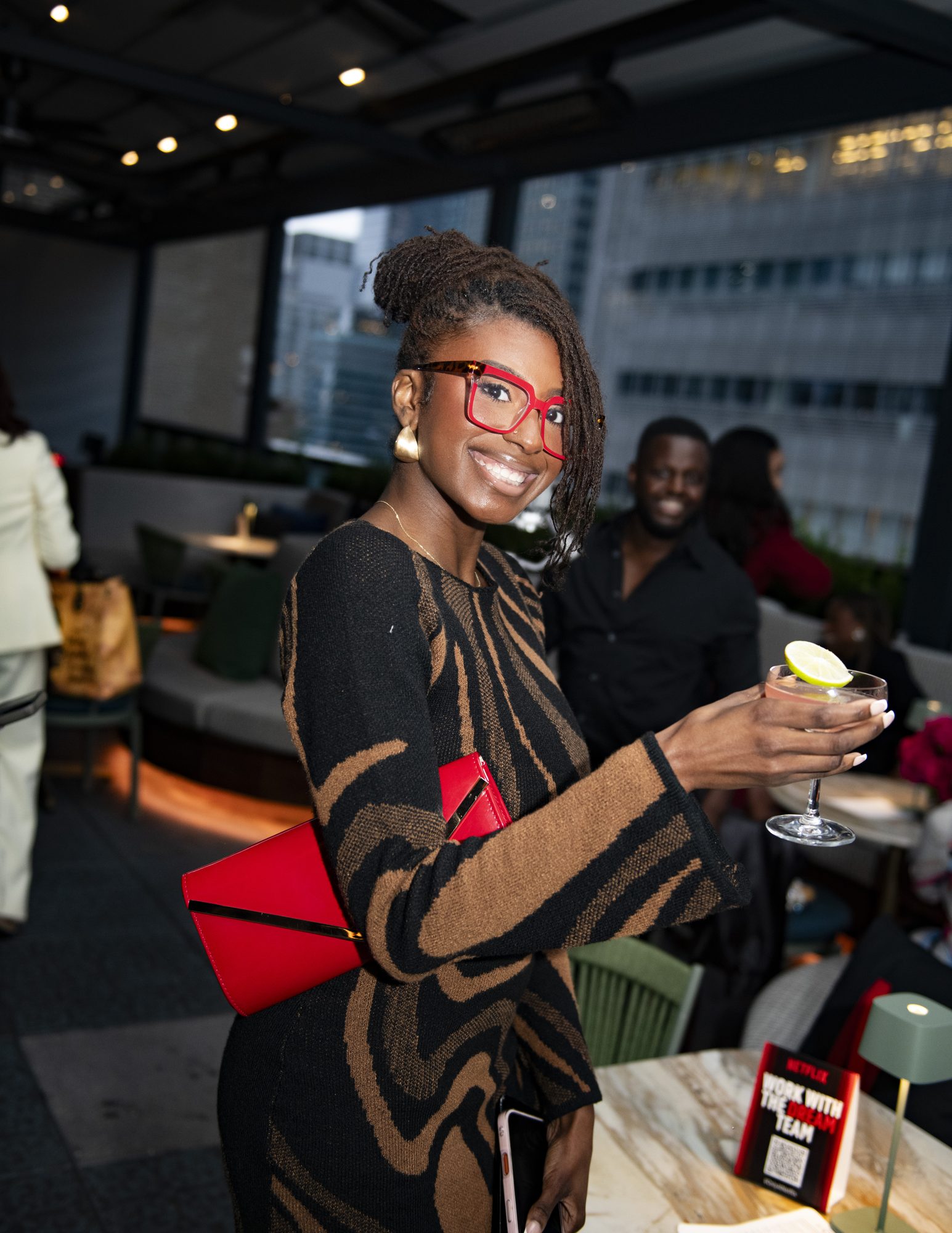 Guest smiling and raising a cocktail on the rooftop