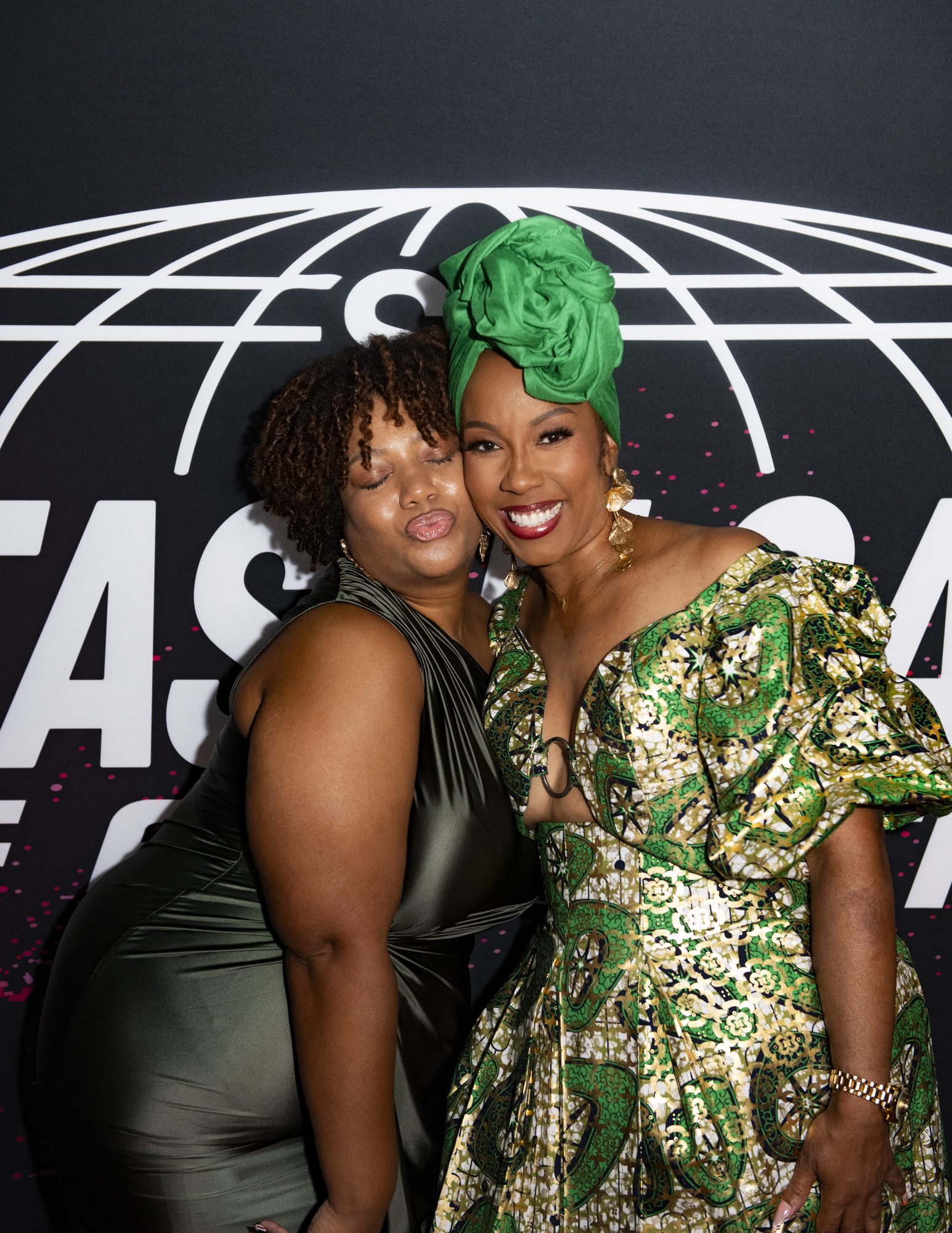 Two guests posing cheek to cheek at the Sistas in Sales step-and-repeat