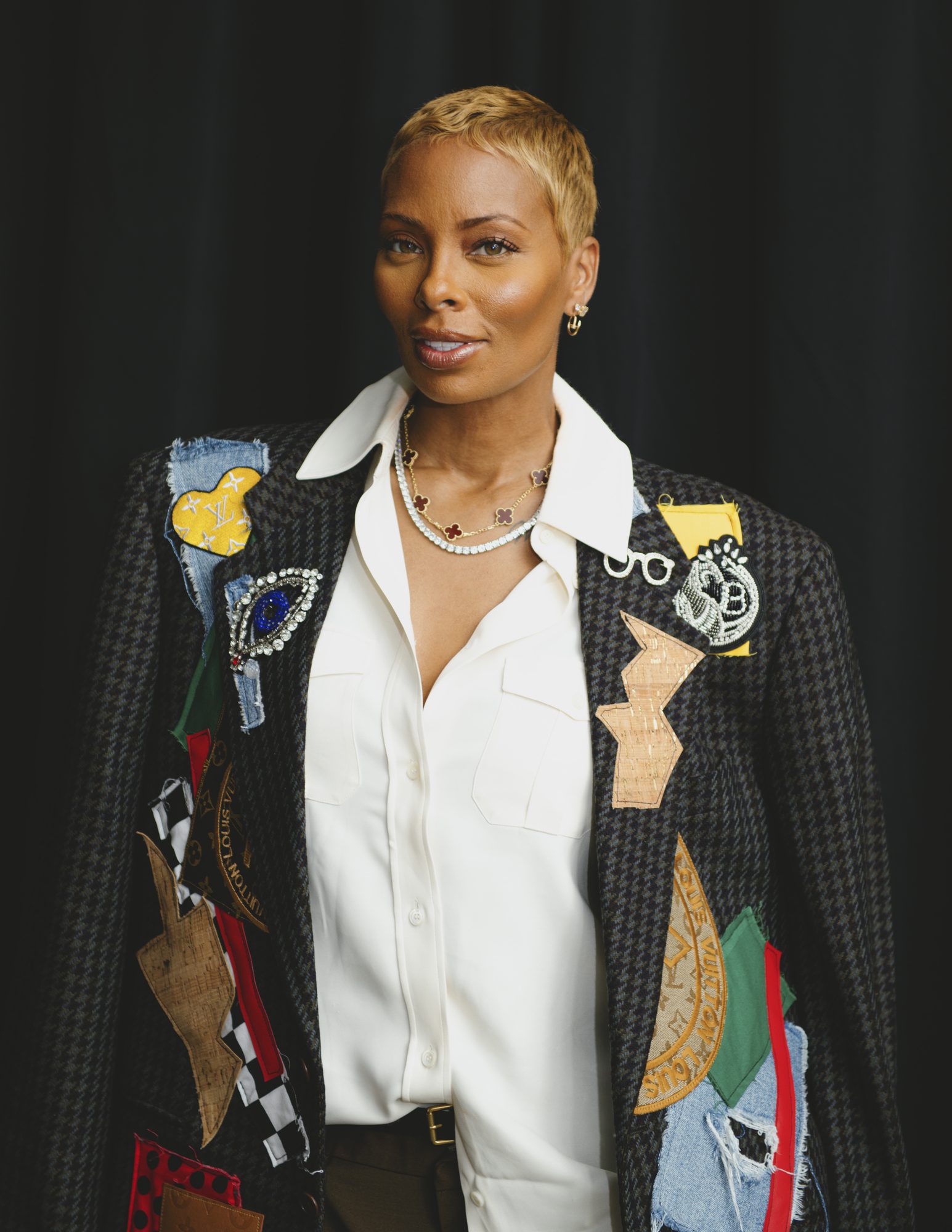 Portrait of a woman in a patchwork jacket against a dark backdrop
