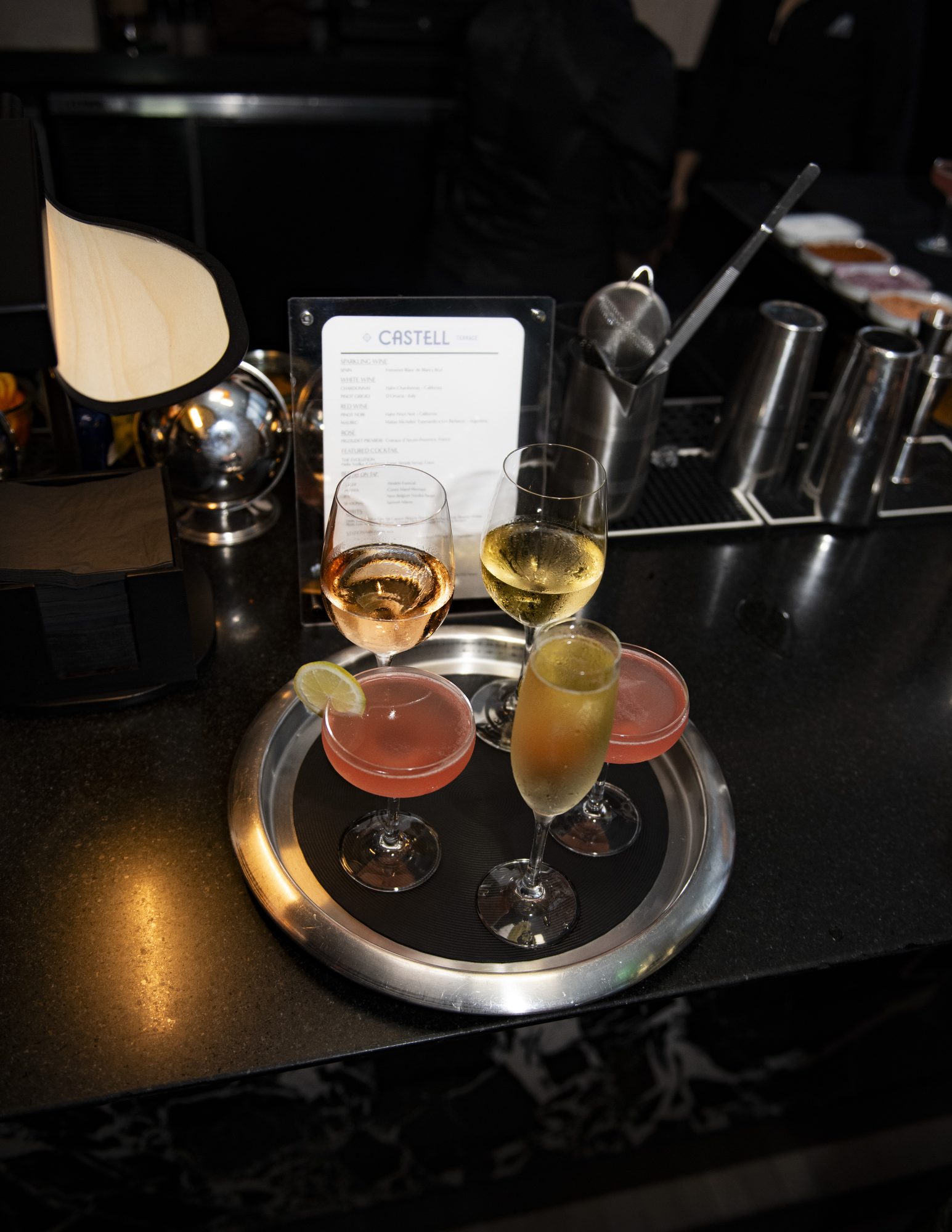 Tray of cocktails and sparkling wine on a dark bar counter